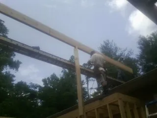 Carpenter setting a ridge beam over a new addition frame — Ice Dam Removal by Roofing Brothers in Delia