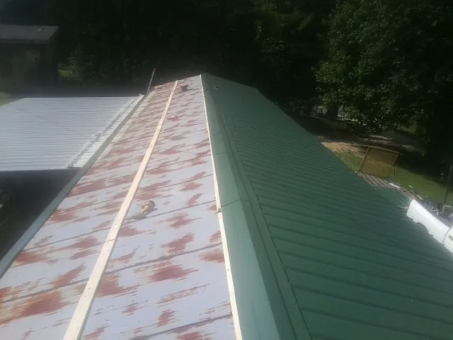 Old rusted panels beside newly installed green metal roofing — Wind Damage Roof Repair by Roofing Brothers in Delia