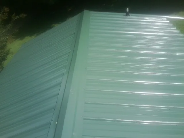 New green metal panels meeting at the ridge of a roof — Flat Roof Repair work by our crew in Delia