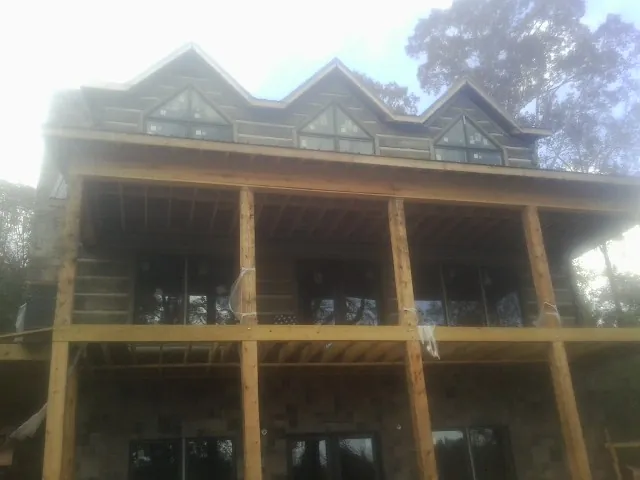 Dormers and porch framing on a large log home under construction — Roof Coating work by our crew in Delia