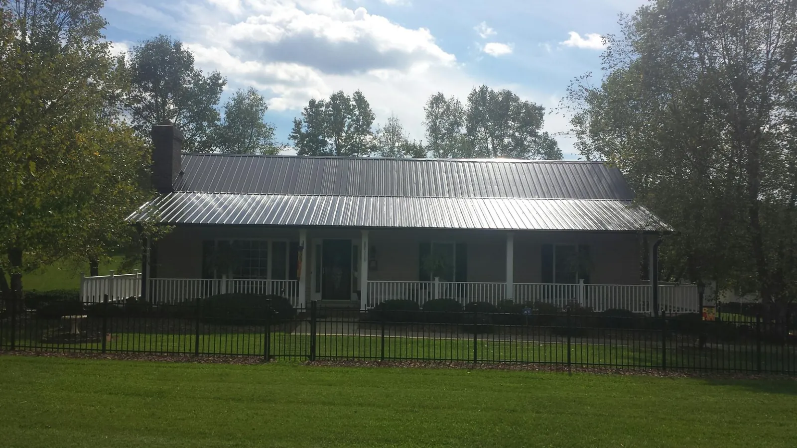 Gray metal roof on a brick ranch with a full width front porch — Gutter Guard Installation work by our crew in Delia