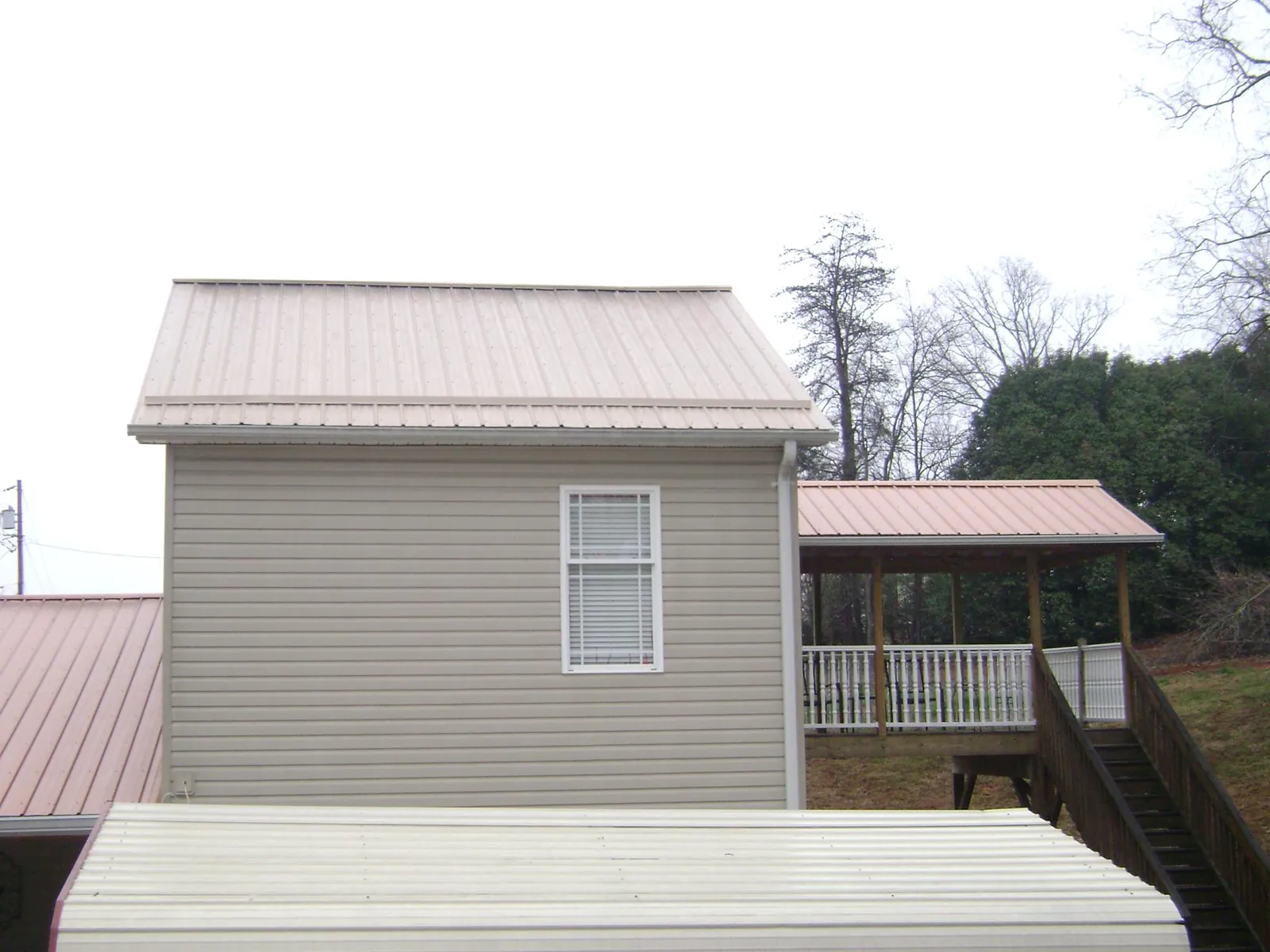 Tan metal roofs on a two story addition and attached porch, from a Roof Replacement job in Delia