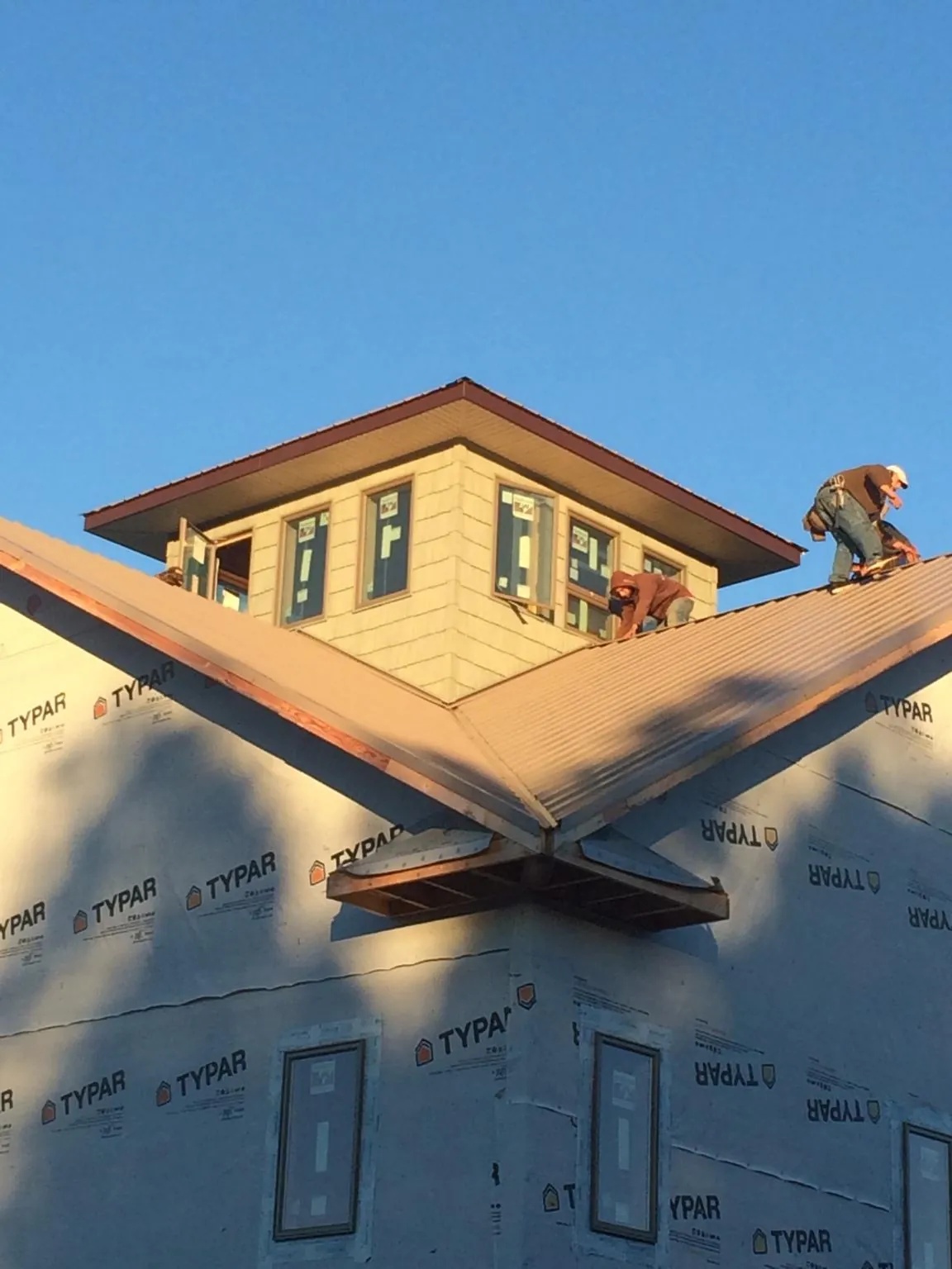 Roofers working around a rooftop cupola on a new metal roof at sunset — Roof Waterproofing in Delia by Roofing Brothers